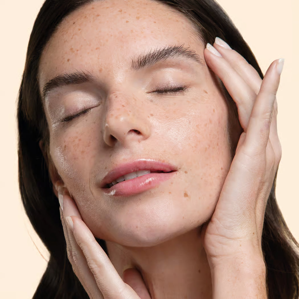 Woman with hands on her face against a beige background
