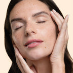Woman with hands on her face against a beige background