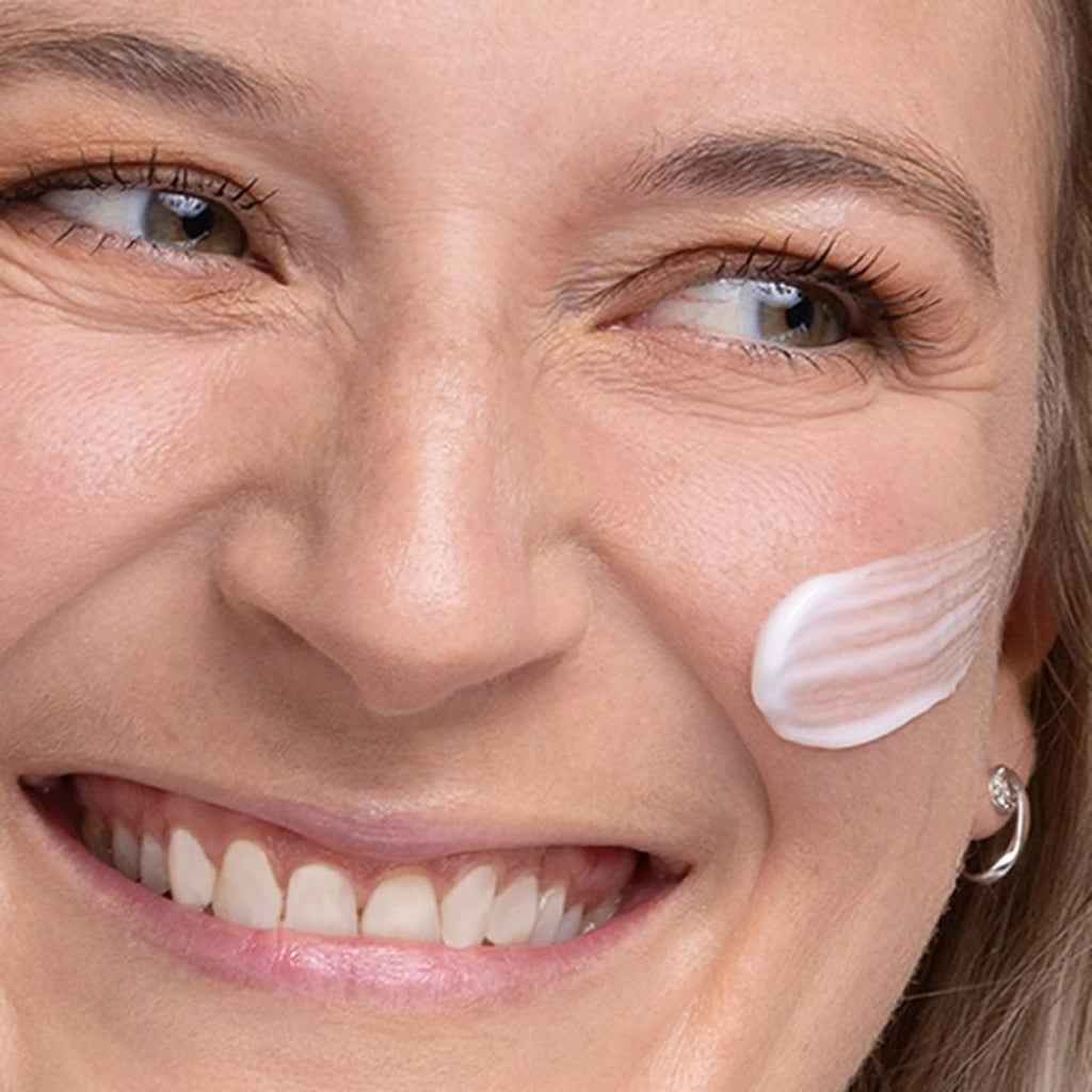 Close-up of a woman's face with a skincare product applied to her cheek.