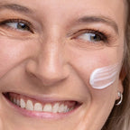 Close-up of a woman's face with a skincare product applied to her cheek.