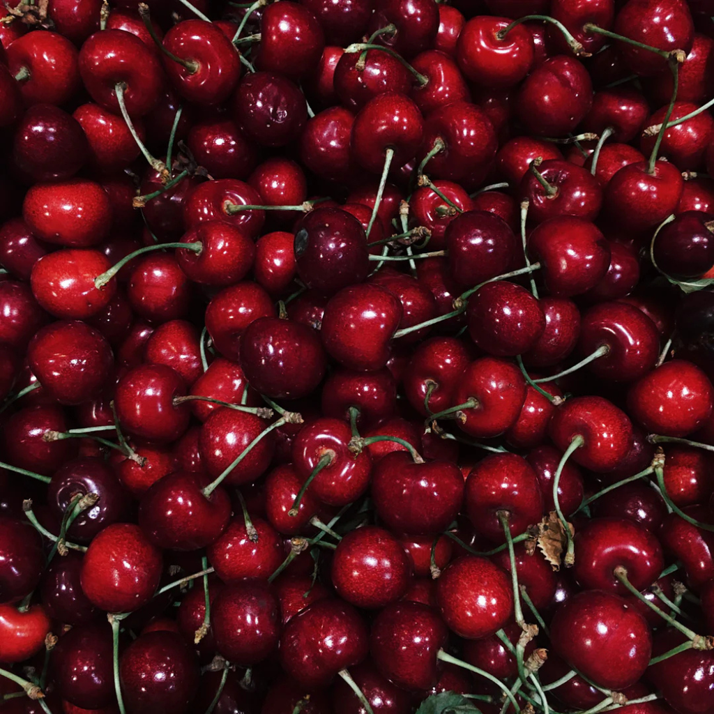 Close-up of a pile of red cherries with stems.