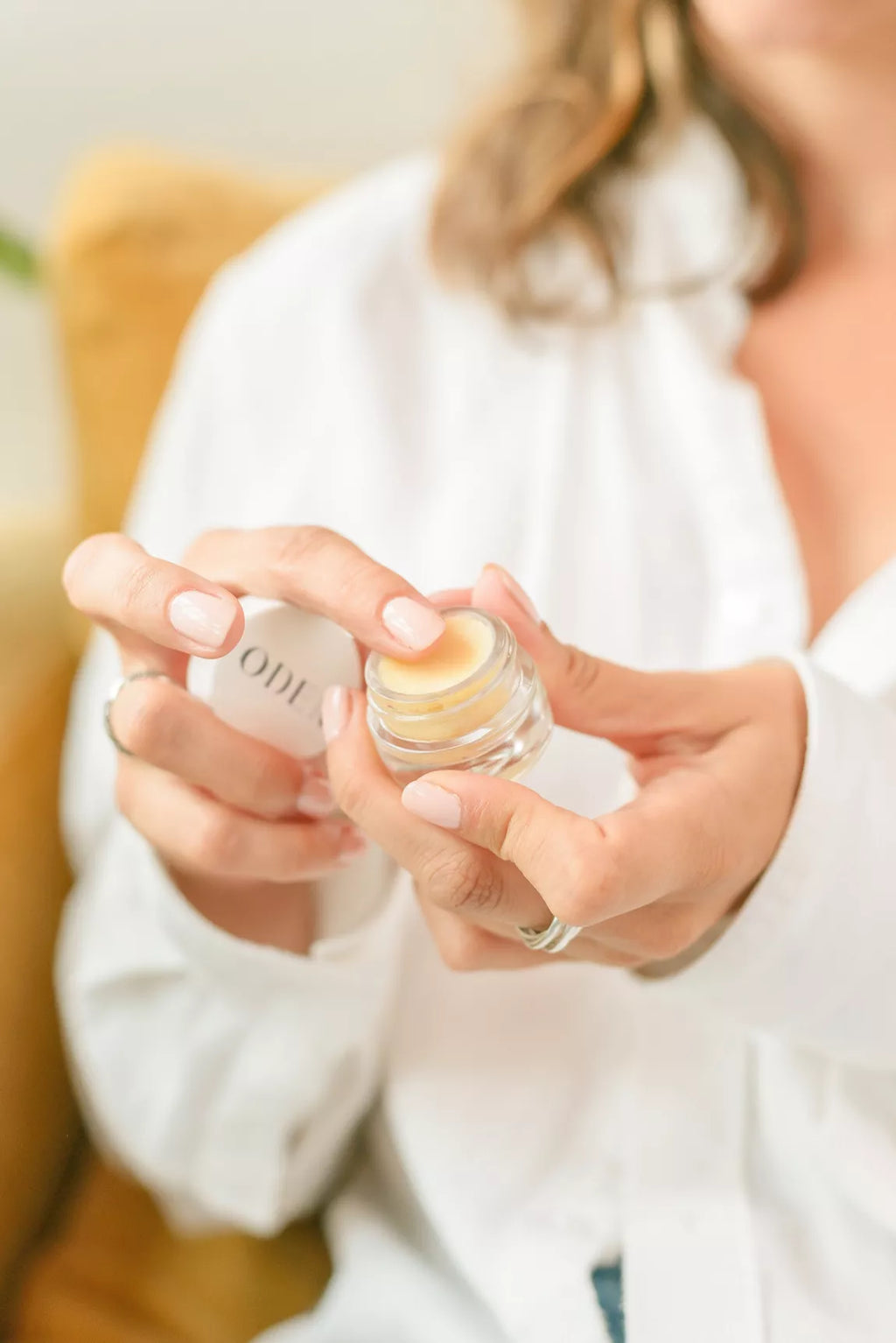 Person holding a small container of lip balm with a visible brand name.