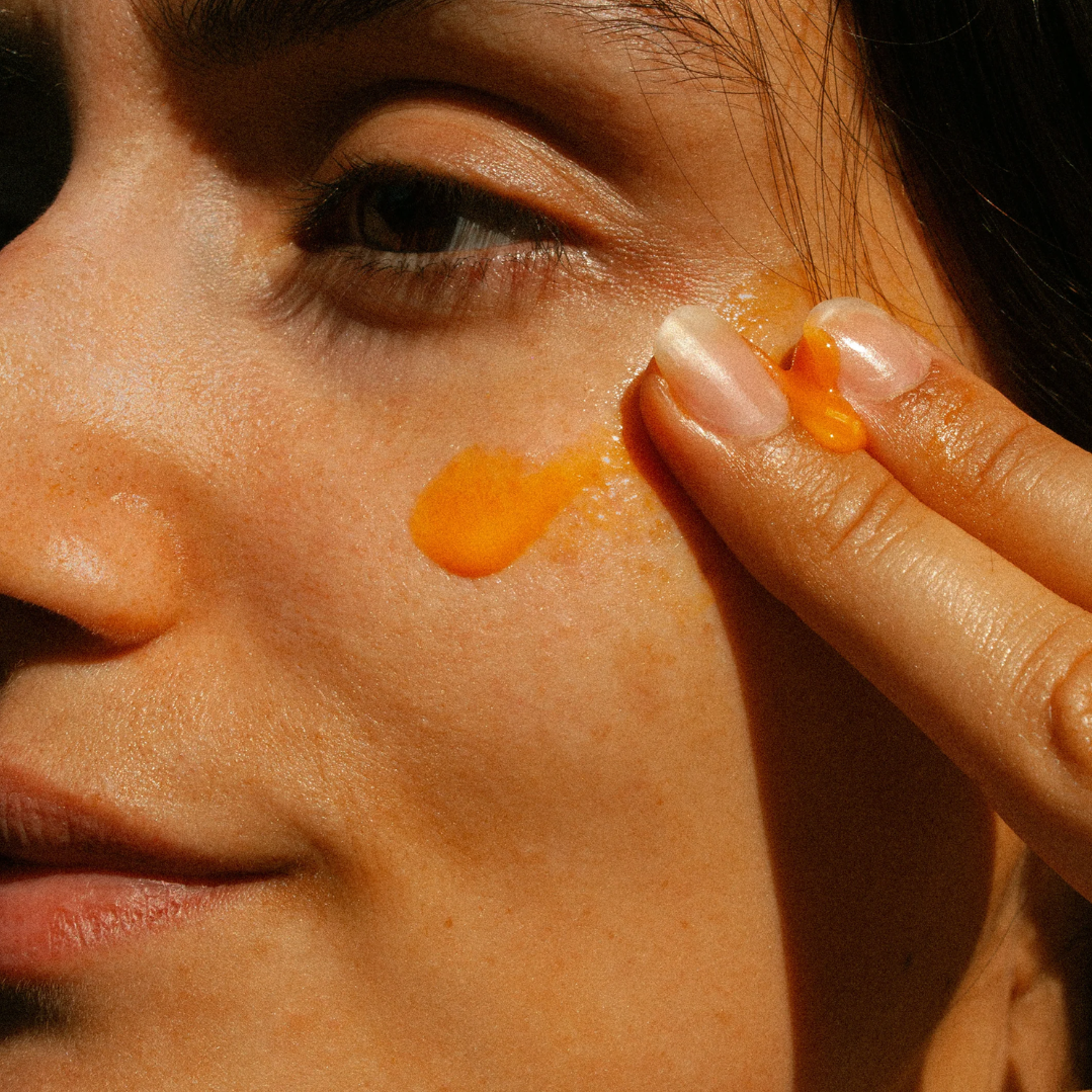 Close-up of a person applying oOden_radiance serum to their face.