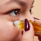 Close-up of a woman applying oil to her eye with a dropper.