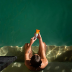 Person in a pool holding a sunscreen tube above water - sun_kissed_lotion_spf50