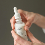 Hand holding a bottle of vielo organic hyaluron serum against a neutral background