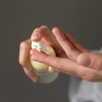 Hand holding a Vielö organic face cleaning milk with a dark background