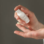 Hand holding a Vielö Organic eye cream bottle against a dark background